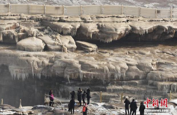 12月6日，游客在山西省临汾市吉县黄河壶口瀑布景区欣赏冰挂景观。