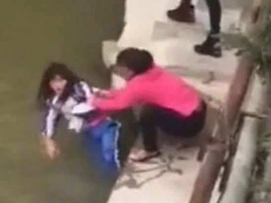 视频显示,一名中年妇女抓着一名穿校服的女生,作势将其推入河中,女孩