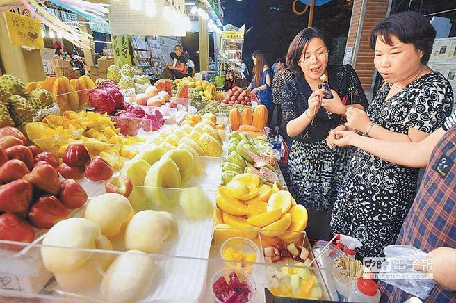 两名大陆游客在台湾水果摊位前试吃,称赞台湾水果好甜.