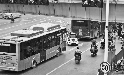 郑州市东风路上,一辆老年代步车在两辆公交车的夹缝中穿梭.