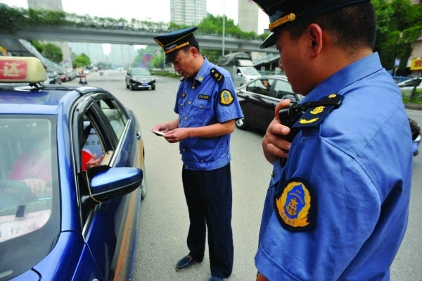 市运管局稽查二大队的工作人员佩戴执法记录仪,对出租车进行例行排查.