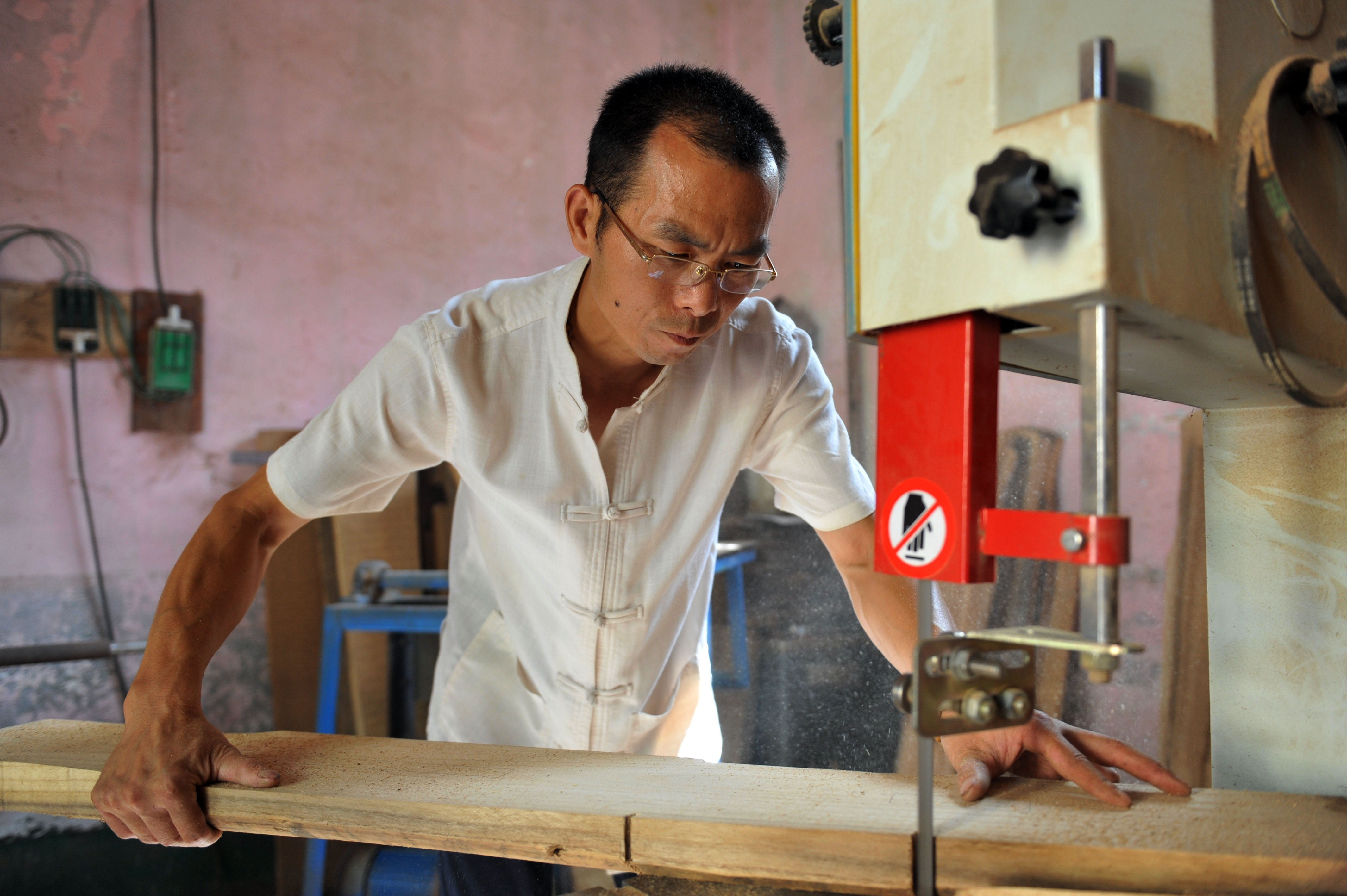 2016年6月24日,河南省沁阳市清平村斫琴人汪新院在电锯上制作琴胚.图片