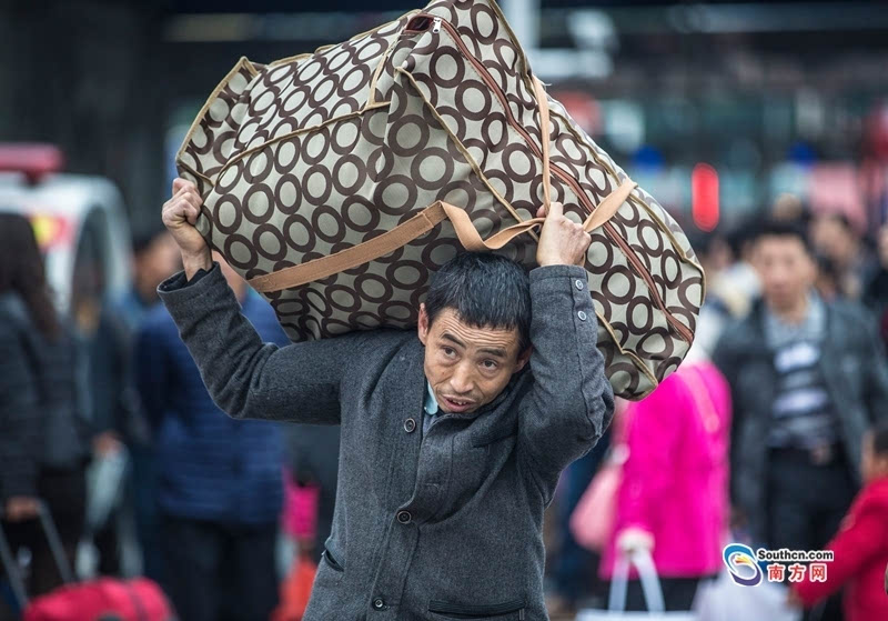 一名男子扛着沉重的行李走入广州火车站.