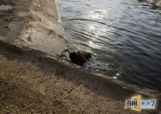 天热时,小男孩在河里游泳.