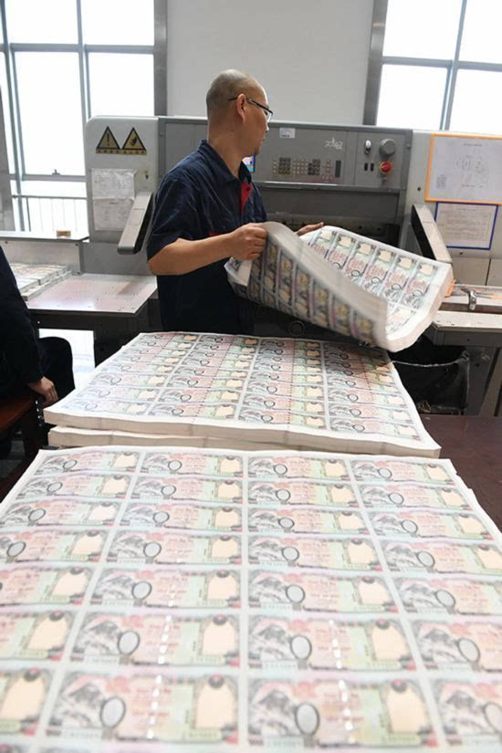 南昌印钞有限公司的工作人员在将整版的卢比送入机器内进行裁切(2月23