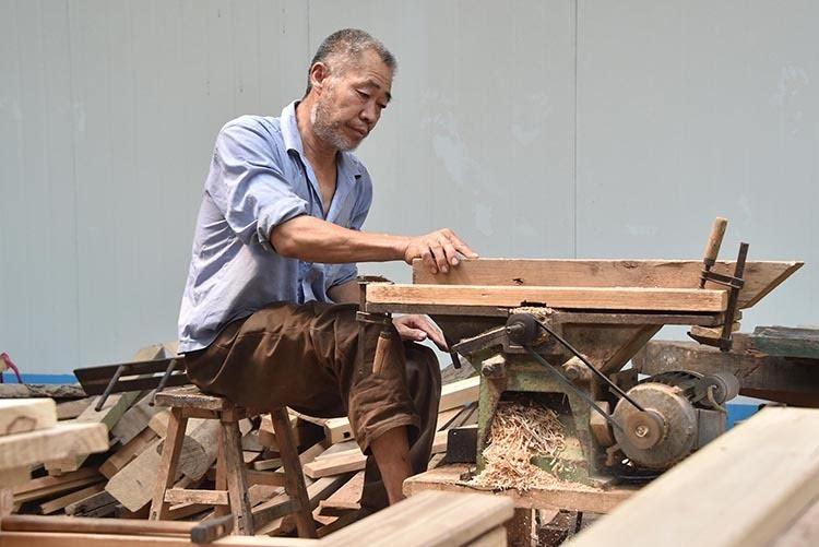5月22日,赵树焕(右二)在木器加工厂给年轻人讲解木器加工的技术要求.