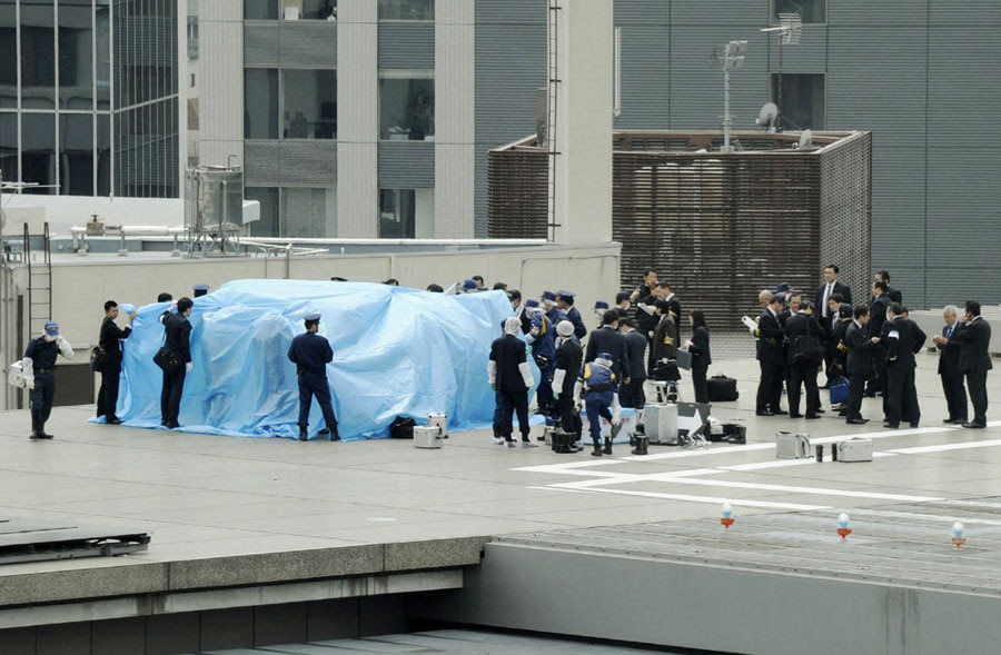 japanese policemen cover with a blue sheet and inspect a small