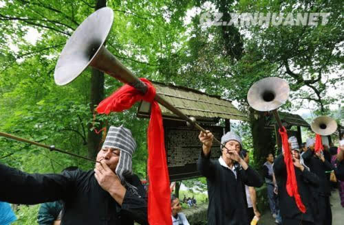 6月12日,鲍塘村村民用长唢呐欢迎游客到来.