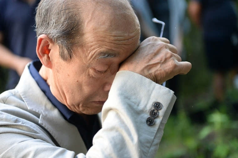 8月10日,在黑龙江省牡丹江市,中岛幼八在养父母墓前回忆当年情景时不