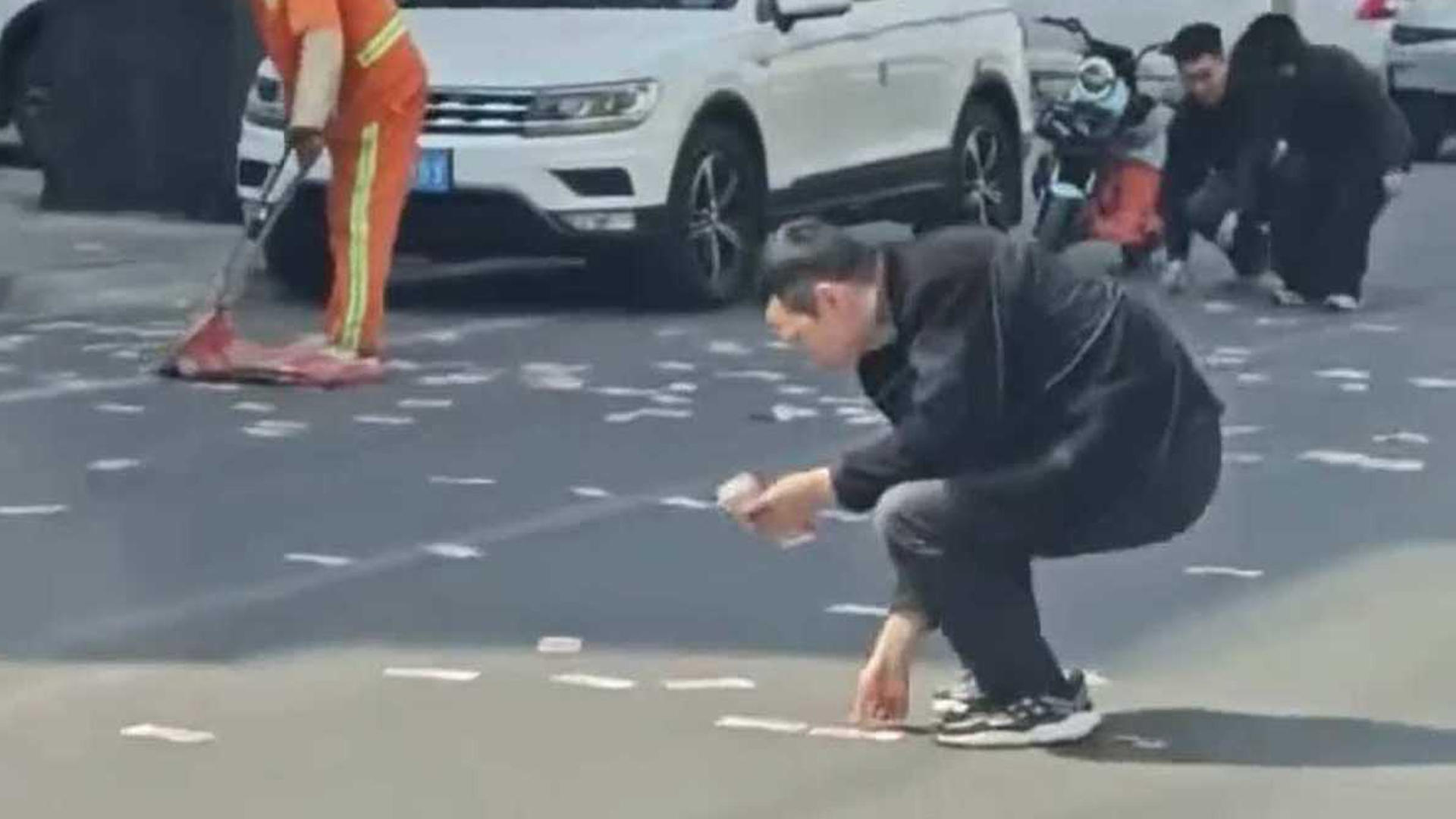 商务车行驶时后备箱大量现金意外飘出，路人满地捡百元大钞，环卫工用扫帚往撮箕扫