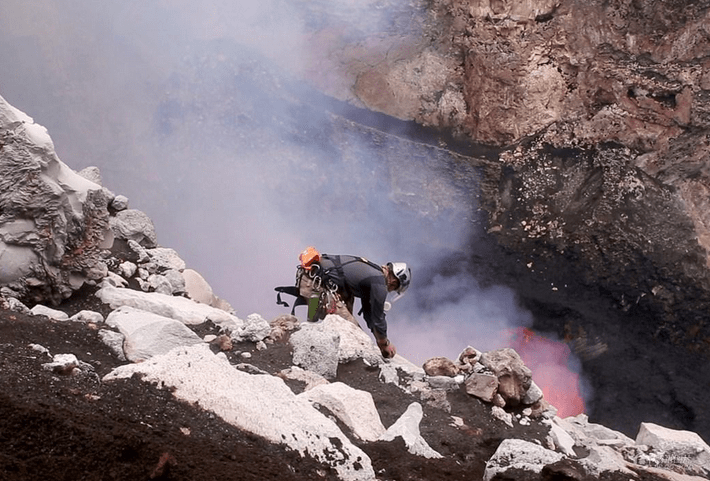 将三明治放到火山口边的岩石上,用一块石头压住