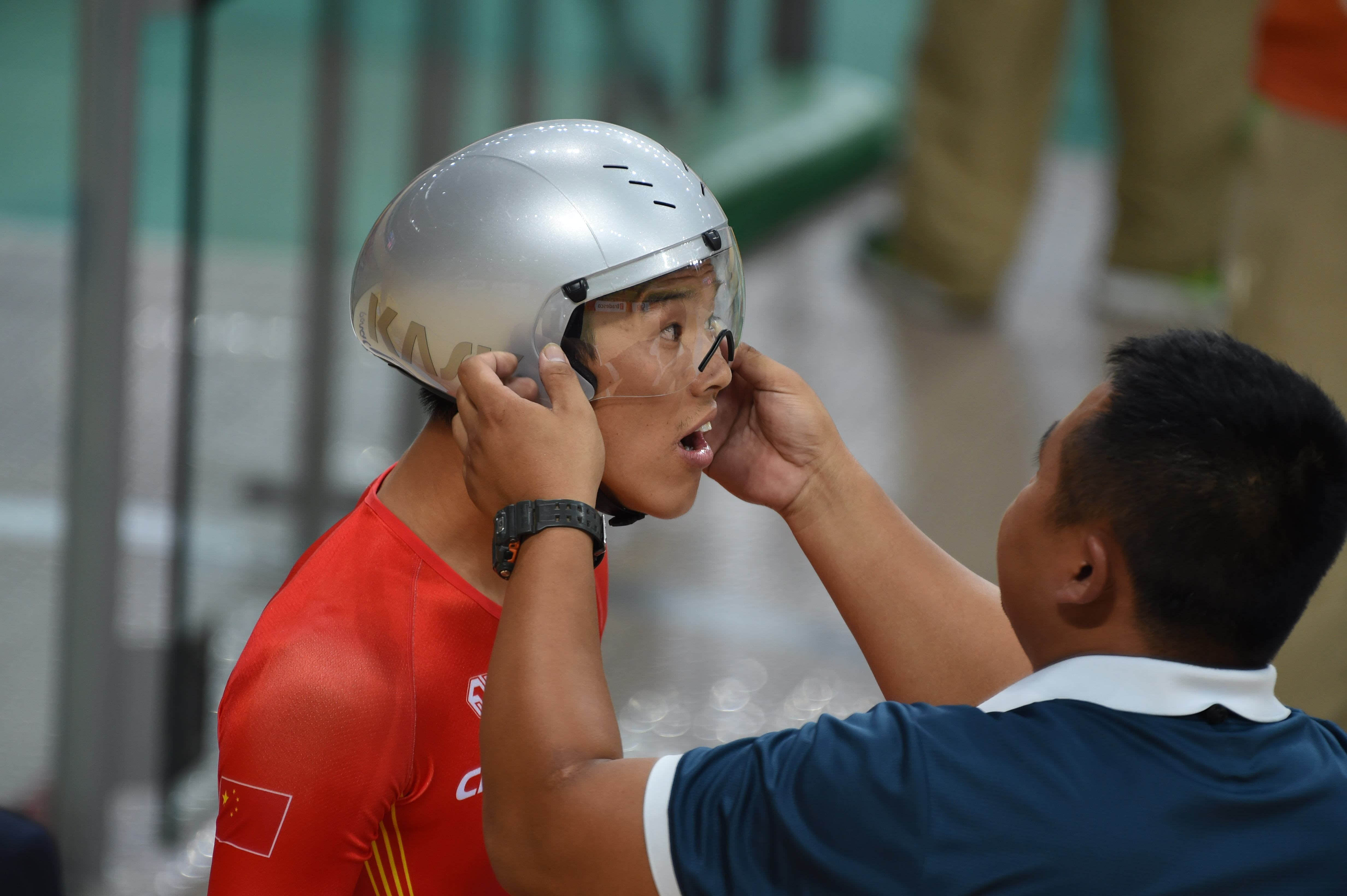 中国残奥自行车队教练刘光锦(右)在赛前帮助选手梁贵华上车