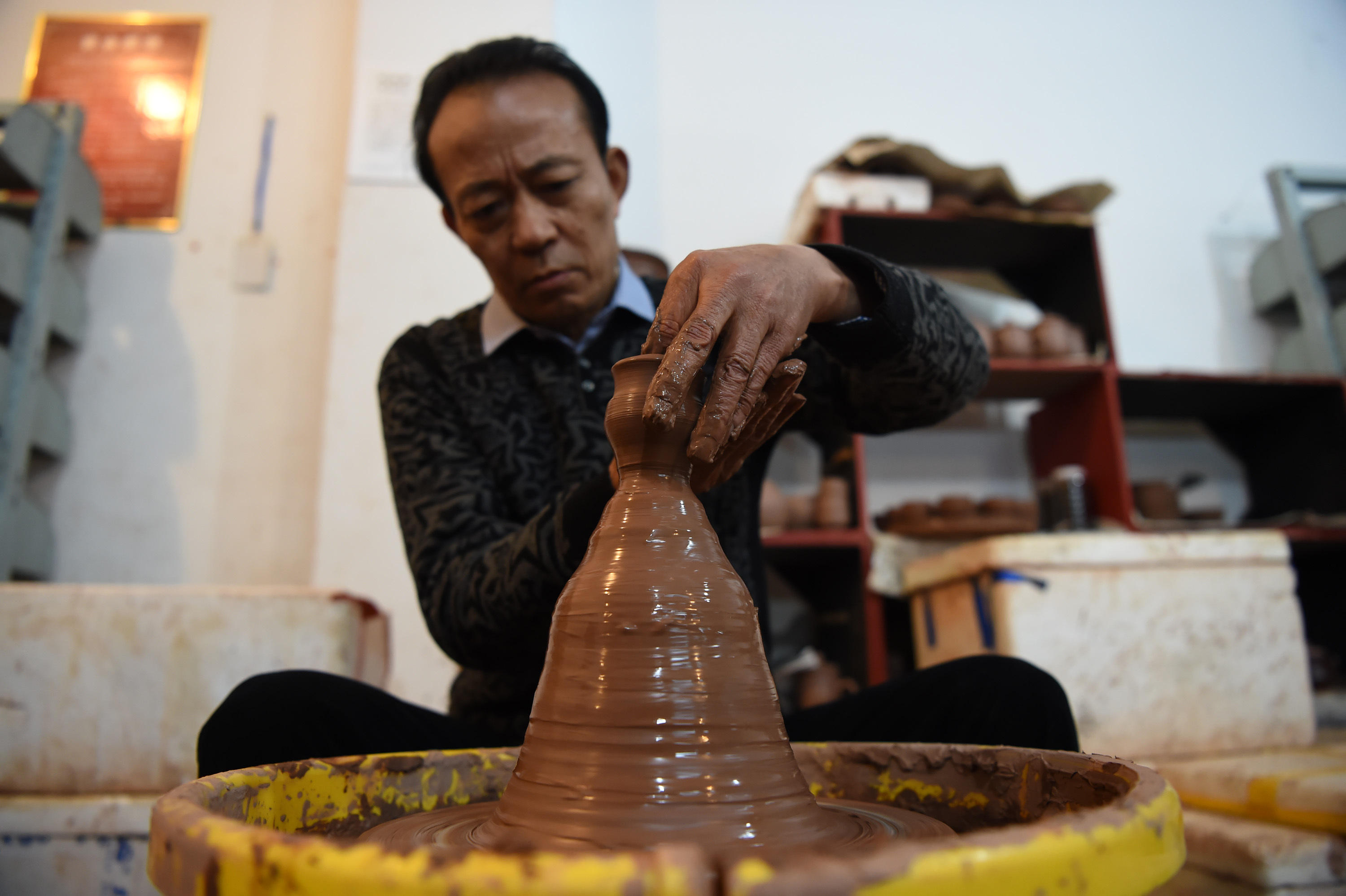 12月14日,梁先才在展示手拉坯的制陶技艺.