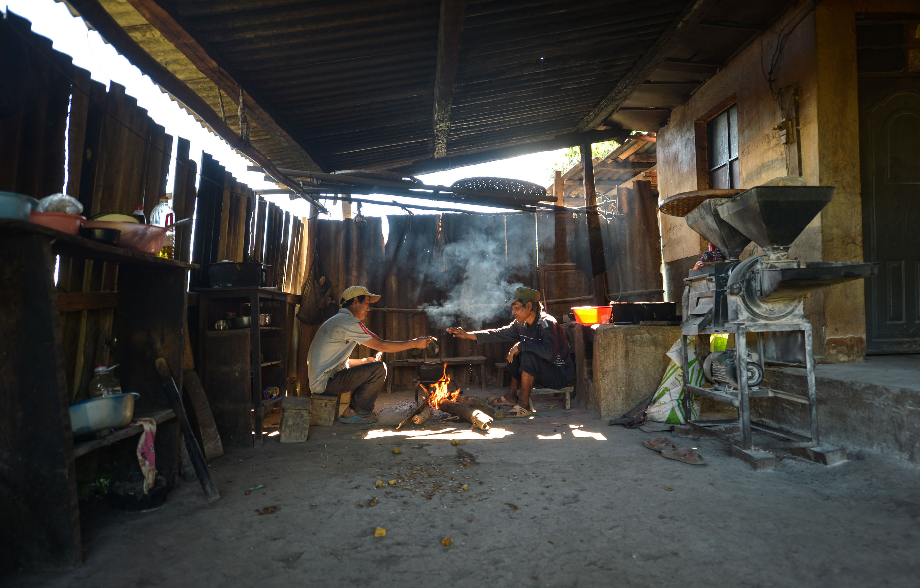 月14日,云南澜沧,拉祜族建档立卡贫困户朱扎嗨(左)在自家老房子前烤火