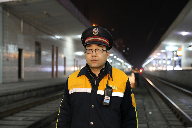 在武汉铁路局襄阳车站各股道间,头戴大檐帽,手拿遥控器,身着黄蓝相间