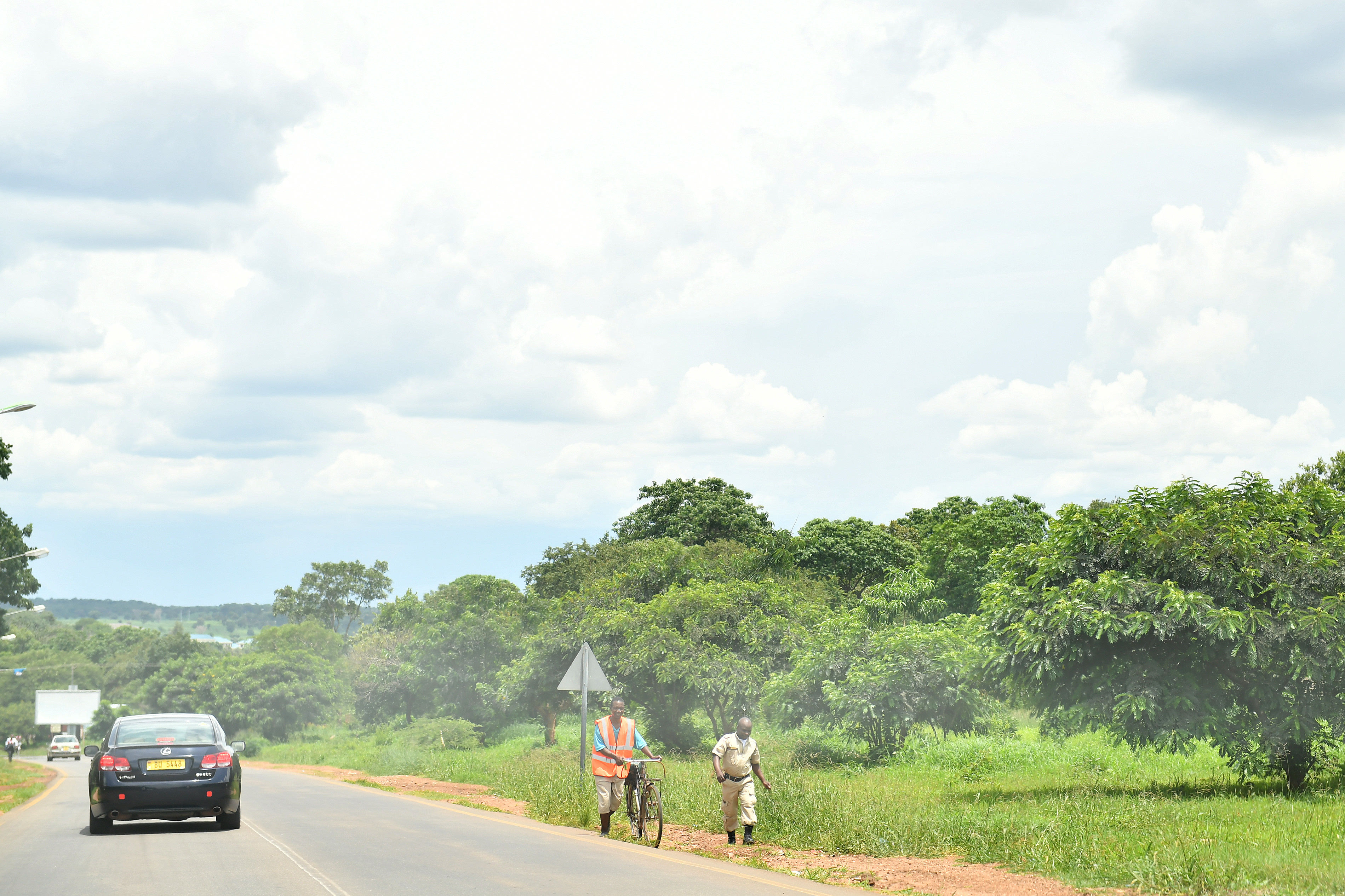 1月30日,在马拉维首都利隆圭,"自行车的士"司机和乘客一同走上山. .