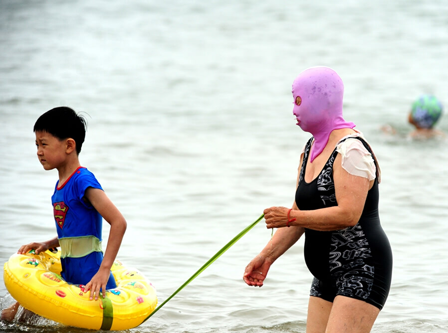 岛城逐渐开启入夏模式,在青岛第一海水浴场,戴着脸基尼头饰的大妈多