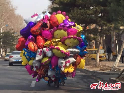 骑电动车后面拴着一百多个气球占了整条马路